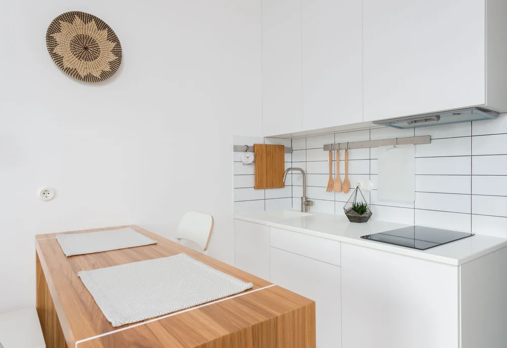A calm kitchen with white benchtops and natural timber furniture